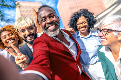 Mensen van verschillende leeftijden, rassen en geslachten glimlachen breeduit buiten een gebouw